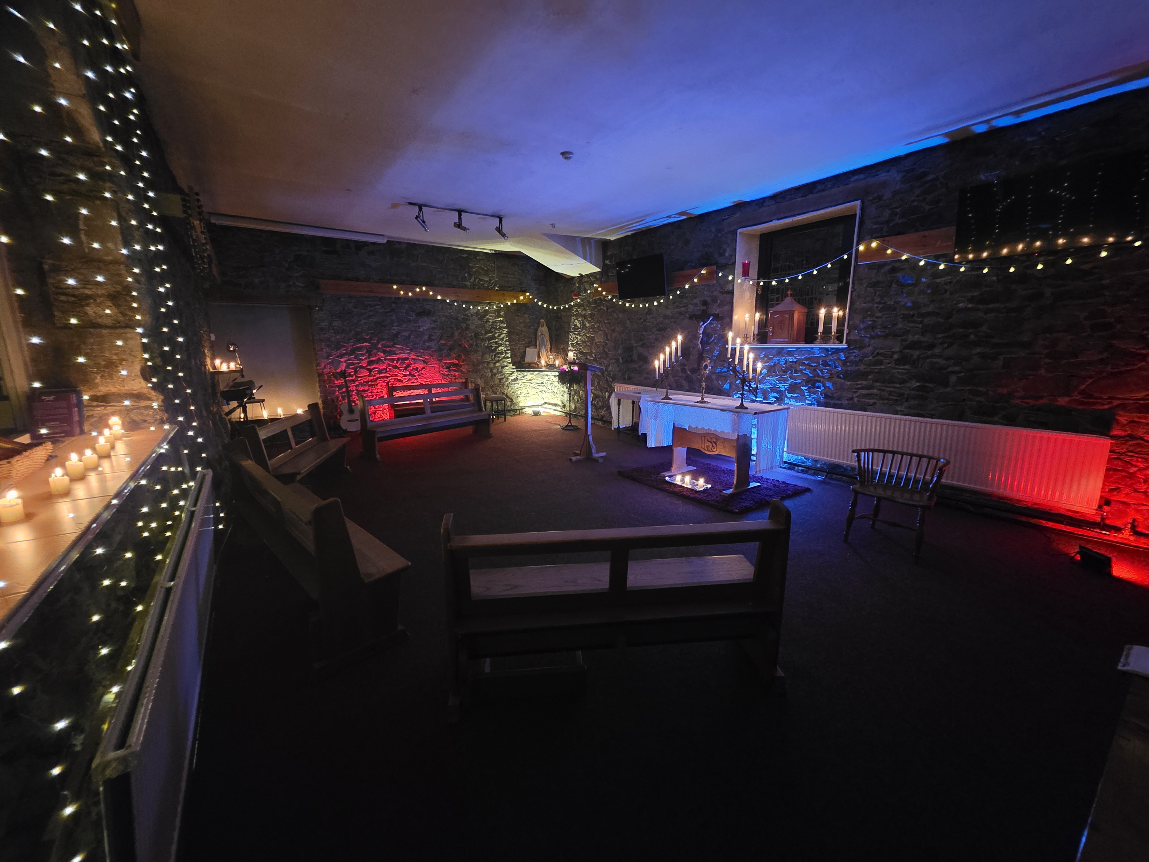 The candlelit stone chapel at Castlerigg Manor, set for prayer with the altar and tabernacle lit