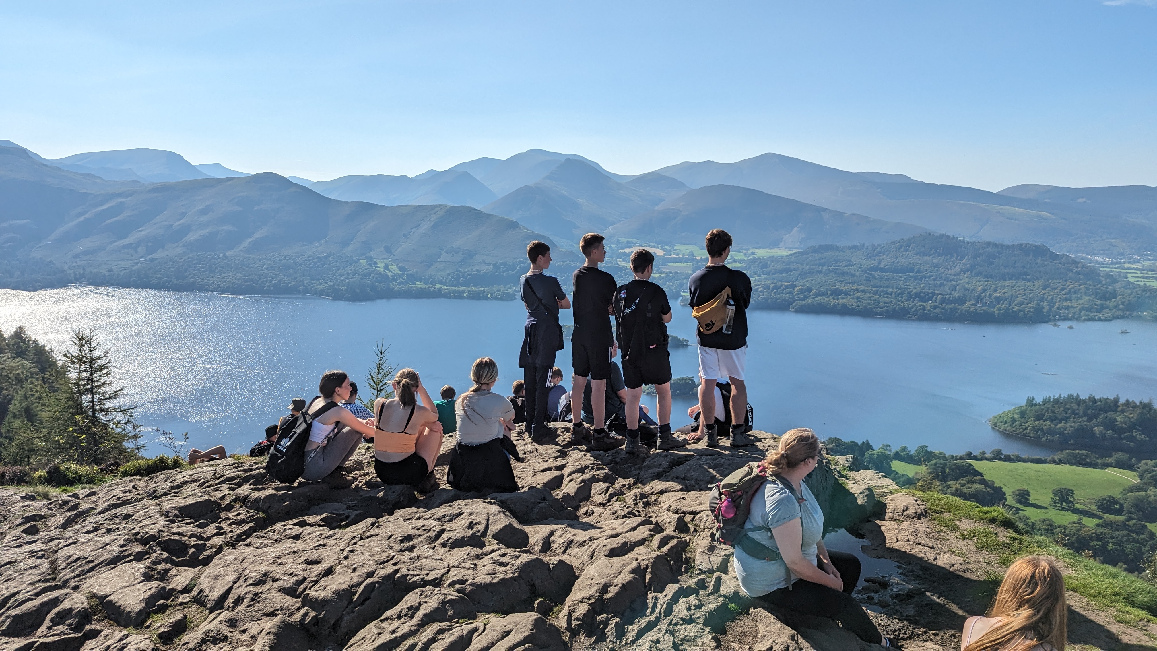 Young people resting at the summit of Catbells looking over Derwentwater