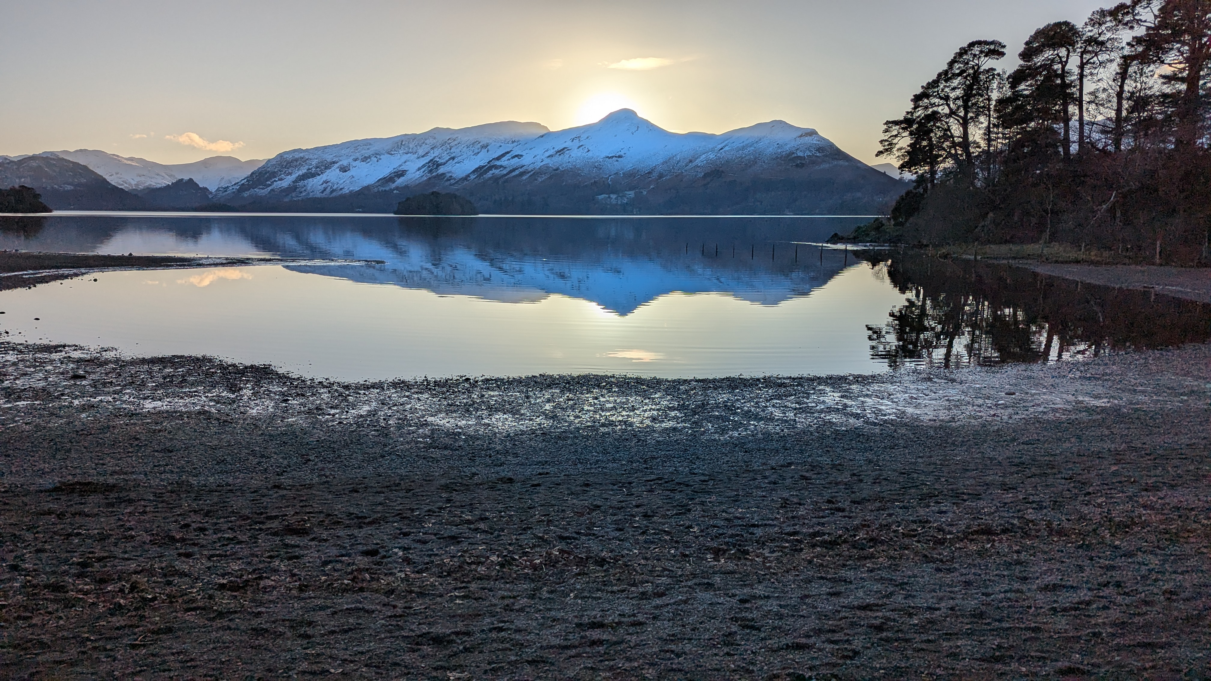 Snow-capped fells reflected in a still Derwentwater at sunrise