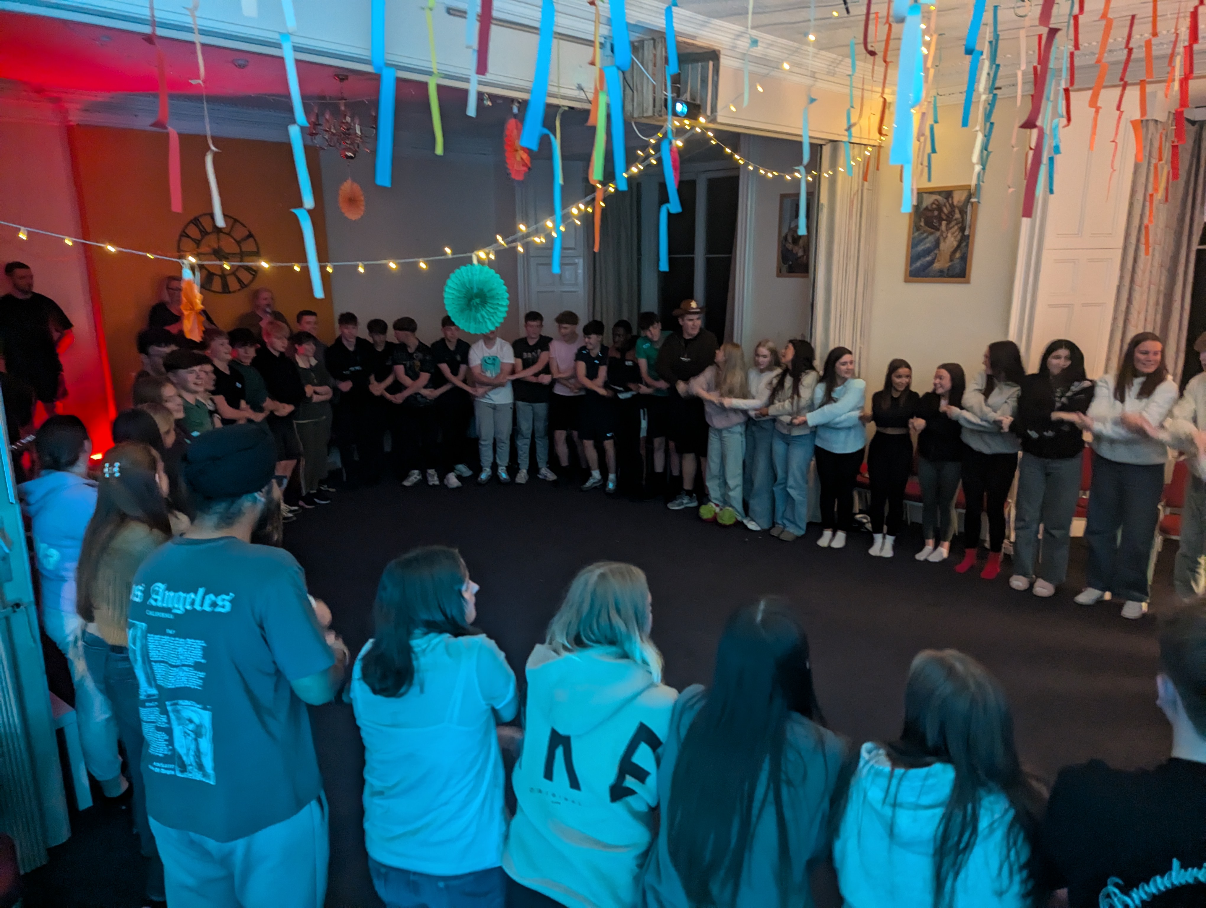 Young people laughing during a group game in the hall