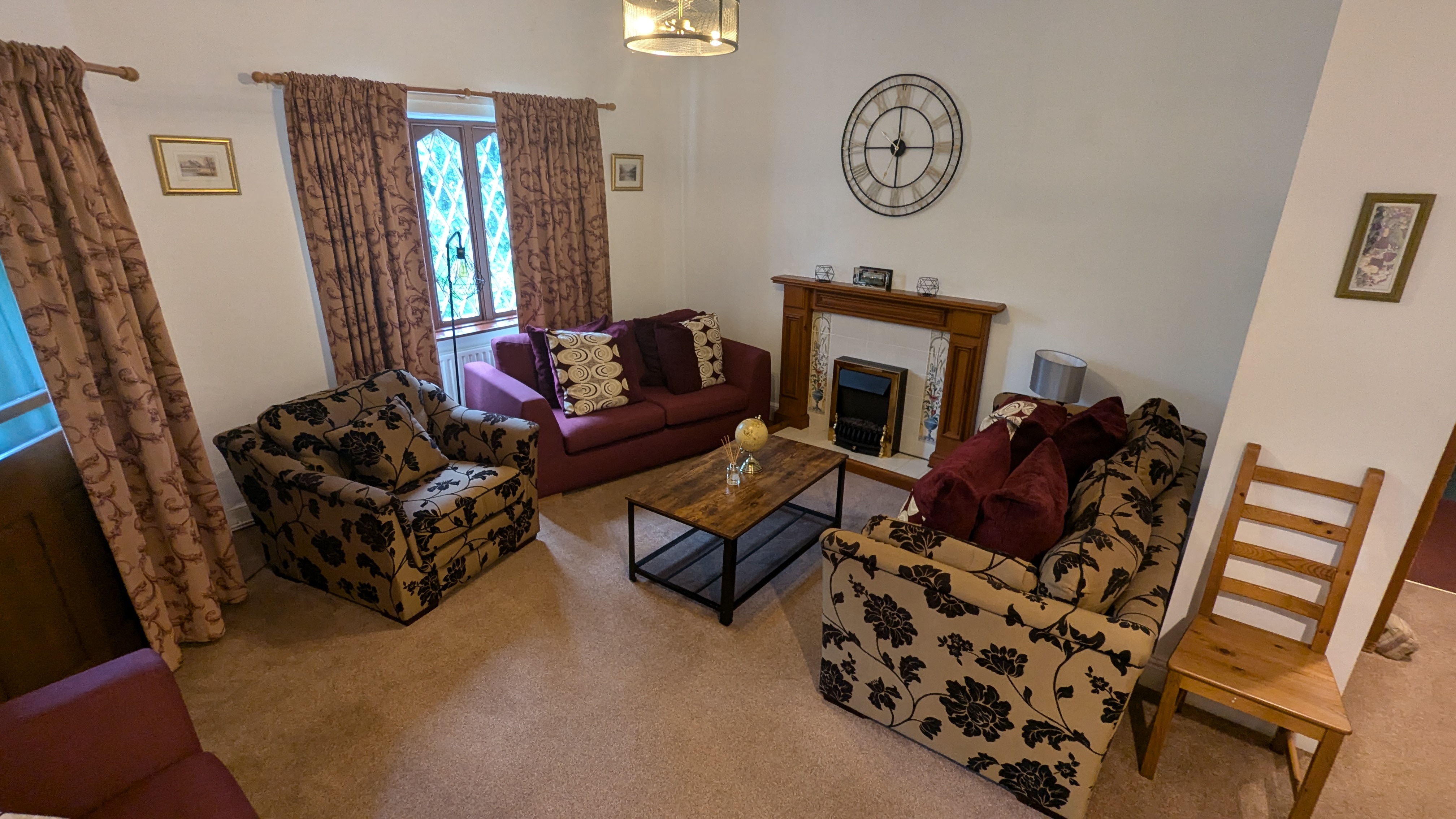 The Guest Lodge lounge with sofas, a fireplace and a large wall clock