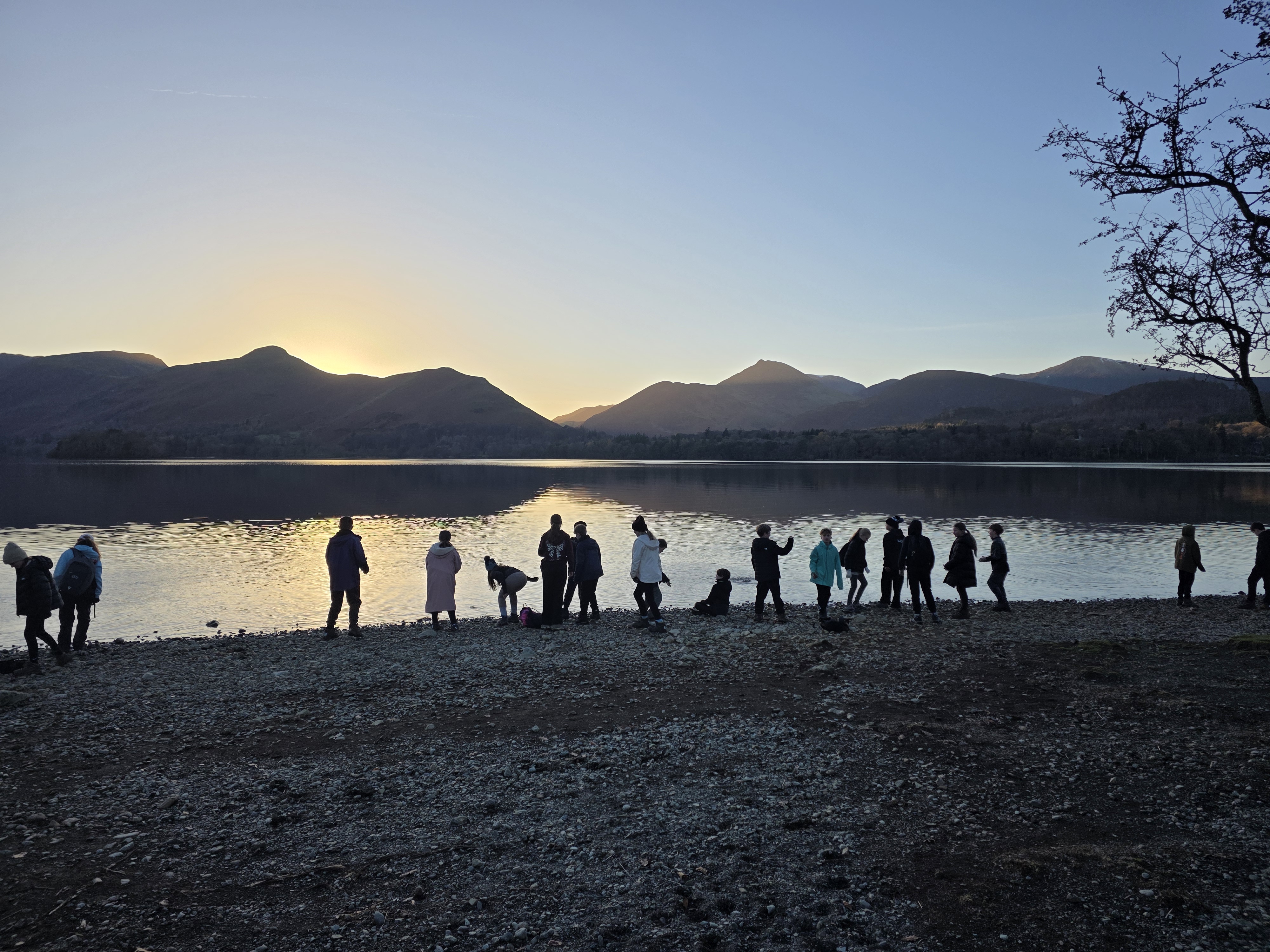 Silhouettes of young people by Derwentwater at dusk