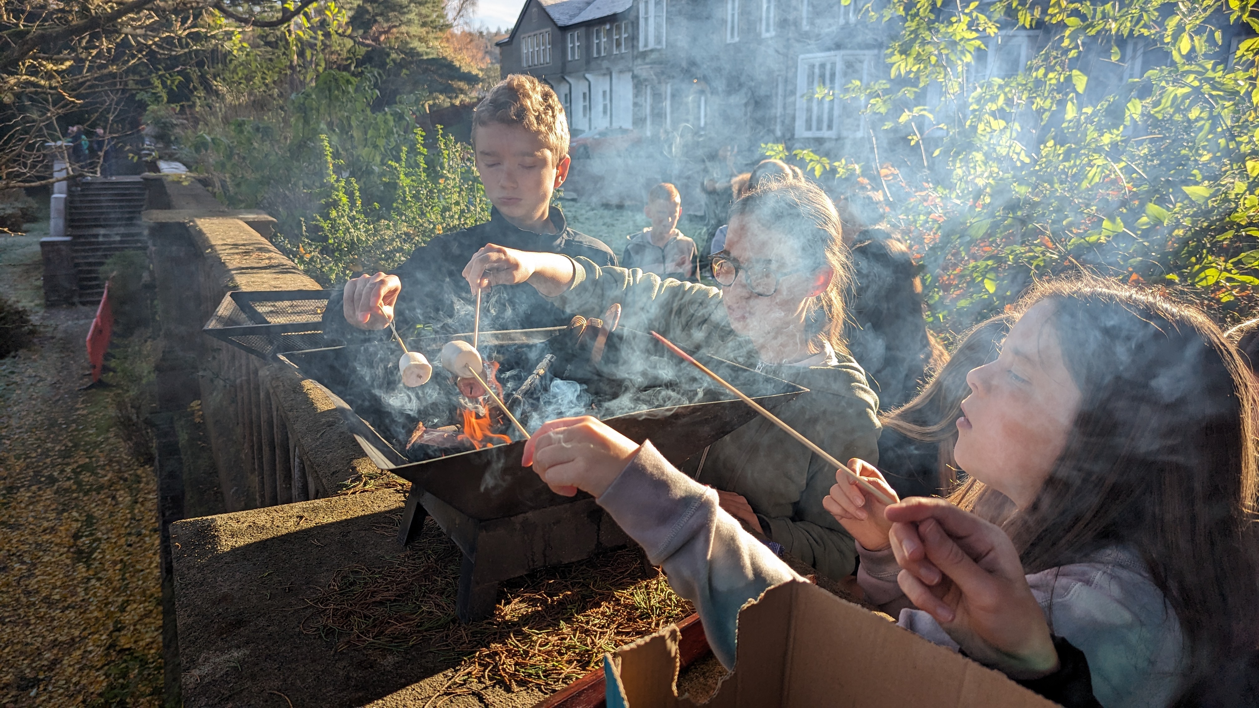 Young people gathered around a fire pit at Castlerigg Manor at dusk